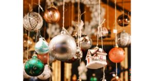 Bunte hängende Christbaumkugeln in verschiedenen Designs, inklusive eines kleinen Hauses, am Stand des Altenberger Dom Weihnachtsmarkts