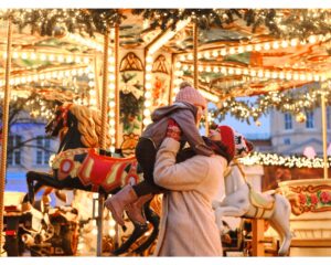 Familie mit Kind auf den Schultern vor dem beleuchteten Nostalgie-Karussell am Altenberger Dom Weihnachtsmarkt 2025