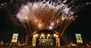 Goldenes Feuerwerk über der beleuchteten Hauptbühne mit jubelnder Menge bei einem Electro-Festival 2025
