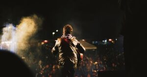 Gitarrist von hinten im Nebel vor begeisterter Menge bei einem Electro-Festival