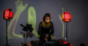 Female Techno-DJ am Pioneer-Controller: rotes LED-Licht, projizierte Hände und konzentrierter Mix in intimer Club-Atmosphäre – kreative Energie und Szene-Vielfalt.