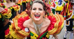 Festivaltänzerin lacht in bunter Tracht bei einer energiegeladenen Straßenparade, dynamischer Tanz, jubelndes Publikum, karnevalistische Stimmung und lebhafte Farben.