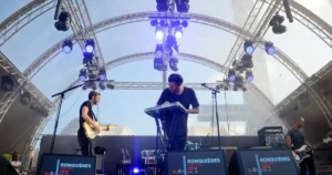 Live-Band bei Ronquières Festival 2014: Gitarrist, Keyboarder und Drummer unter imposanter Bühnenkonstruktion mit LED-Lichtern – energiegeladene Open-Air-Performance.