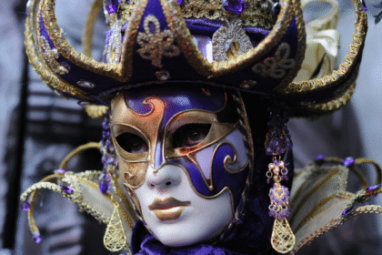 Prächtige venezianische Maske mit violettem Dreispitz, Goldornamenten und Kristallbehang – verkörpert barocke Karnevalspracht.
